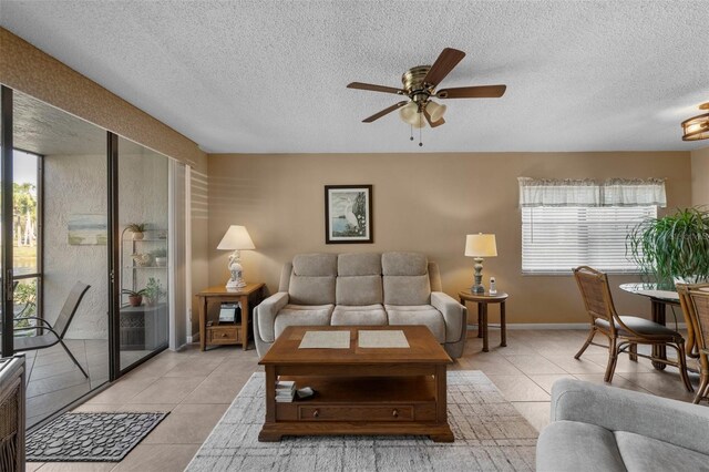 living area with light tile patterned flooring, ceiling fan, a textured ceiling, and baseboards