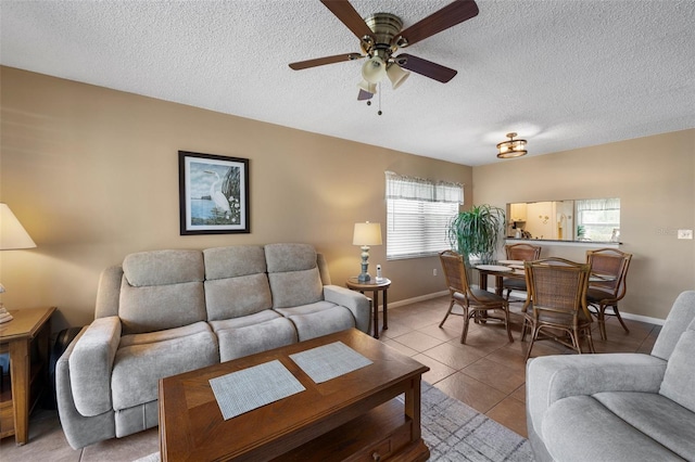 tiled living room with a ceiling fan, baseboards, and a textured ceiling