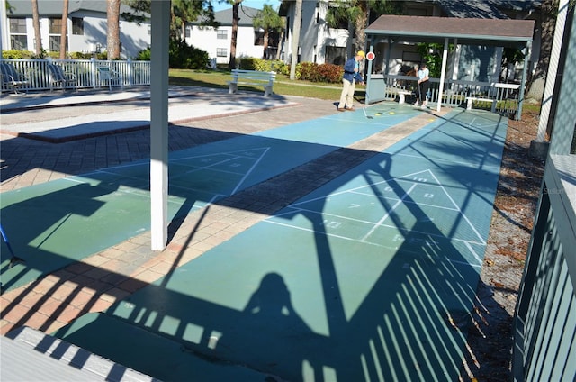 view of property's community with shuffleboard, fence, and a residential view