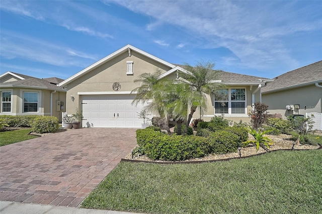 ranch-style house featuring an attached garage, a front lawn, decorative driveway, and stucco siding