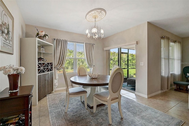 dining space featuring light tile patterned floors, baseboards, and a notable chandelier