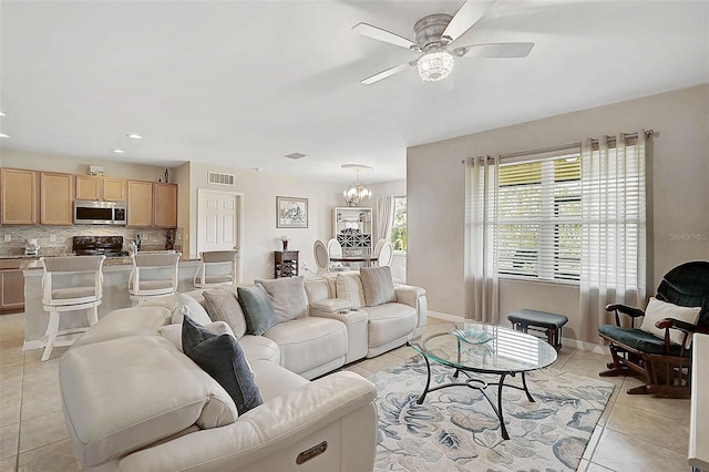 living room with light tile patterned floors, ceiling fan with notable chandelier, visible vents, and baseboards