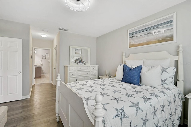 bedroom with baseboards, visible vents, and wood finished floors