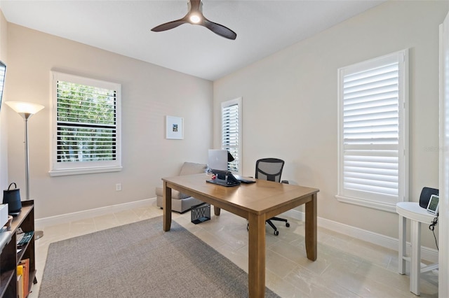 home office with light tile patterned floors, ceiling fan, and baseboards