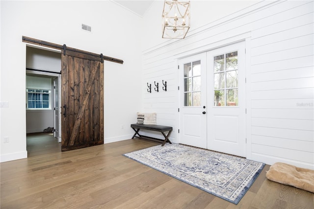 foyer with french doors, visible vents, a barn door, wood finished floors, and baseboards