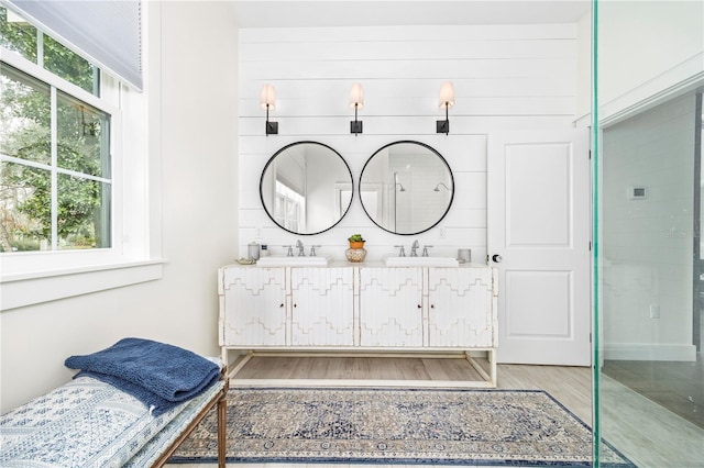 bathroom featuring double vanity, a shower, a sink, and wood finished floors