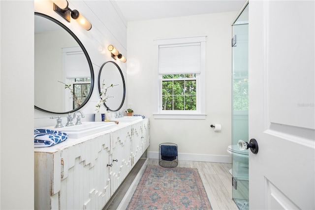 bathroom with double vanity, a sink, baseboards, and wood finished floors