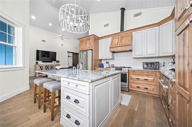 kitchen with a center island with sink, stainless steel appliances, visible vents, hanging light fixtures, and open floor plan