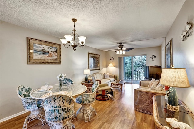 dining room with a textured ceiling, baseboards, wood finished floors, and ceiling fan with notable chandelier