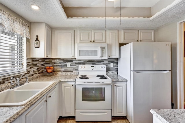 kitchen with white appliances, a sink, white cabinetry, and tasteful backsplash