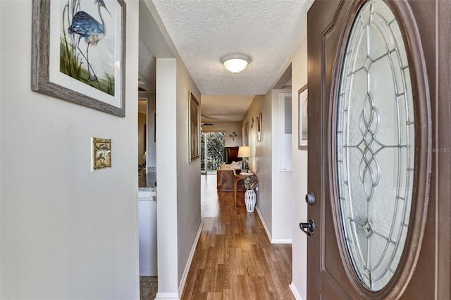 entryway with a textured ceiling, baseboards, and wood finished floors