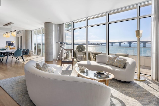 living area featuring a wall of windows, a water view, and light wood finished floors