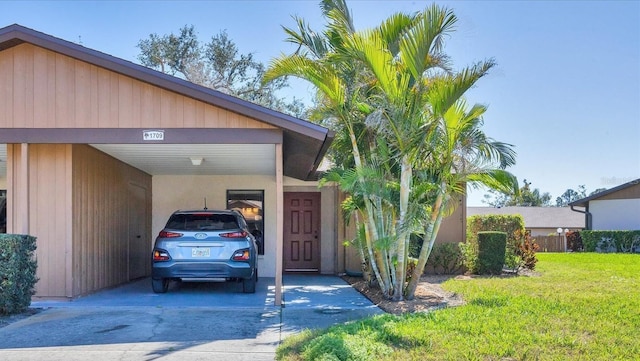 view of front facade with concrete driveway, a front lawn, and an attached carport