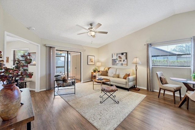 living area featuring a textured ceiling, a ceiling fan, vaulted ceiling, and wood finished floors