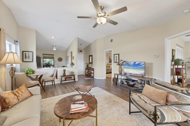 living room featuring lofted ceiling, a ceiling fan, visible vents, and wood finished floors