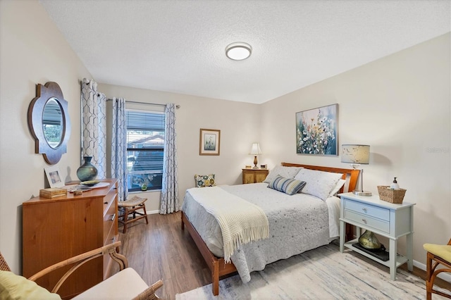 bedroom featuring a textured ceiling, baseboards, and wood finished floors