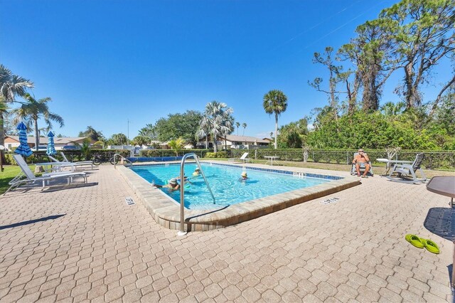 community pool with a patio and fence