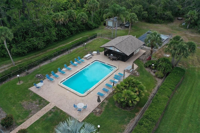 pool with a patio area, a yard, fence, and an outdoor structure