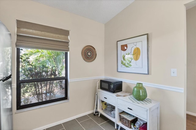 interior space featuring dark tile patterned flooring, a textured ceiling, and baseboards