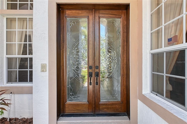 entrance to property featuring french doors and stucco siding