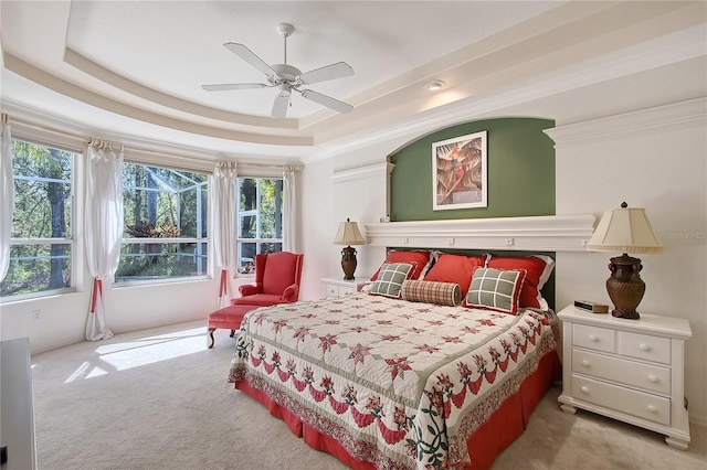 carpeted bedroom with a raised ceiling and ceiling fan