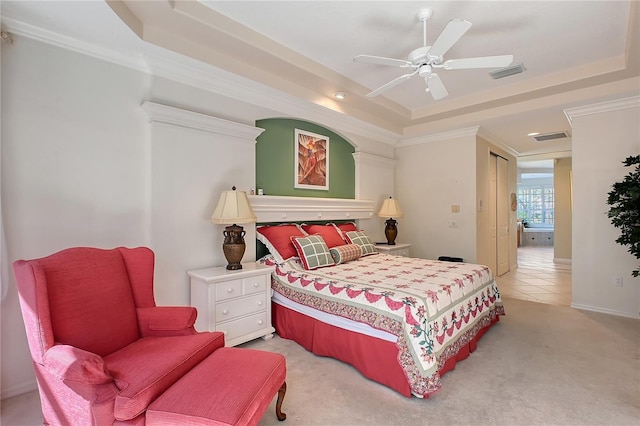 bedroom with a raised ceiling, light colored carpet, visible vents, and ornamental molding