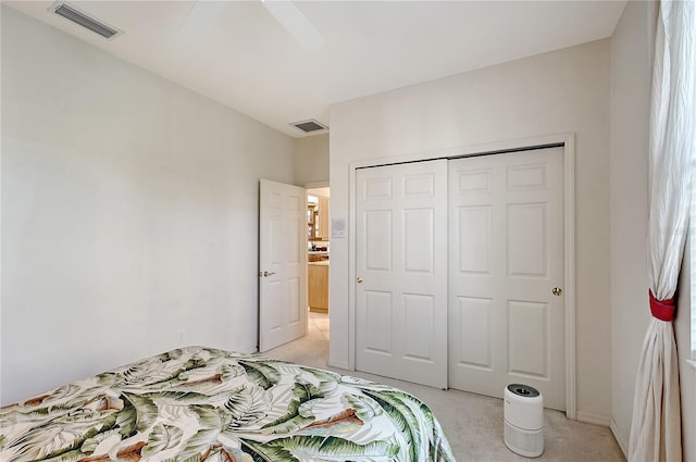 bedroom with visible vents, light colored carpet, a closet, and ceiling fan