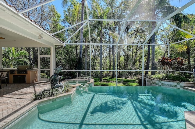 view of pool with glass enclosure, a patio, and an outdoor kitchen