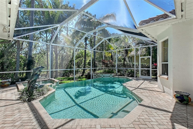 outdoor pool featuring glass enclosure and a patio