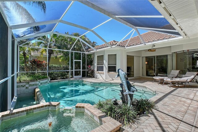 view of swimming pool with glass enclosure, a patio, a ceiling fan, and a pool with connected hot tub