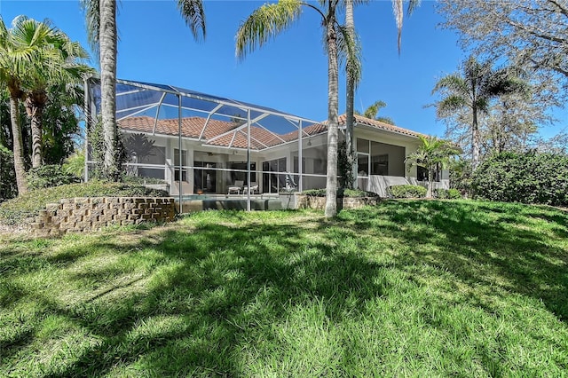 back of property featuring glass enclosure and a yard