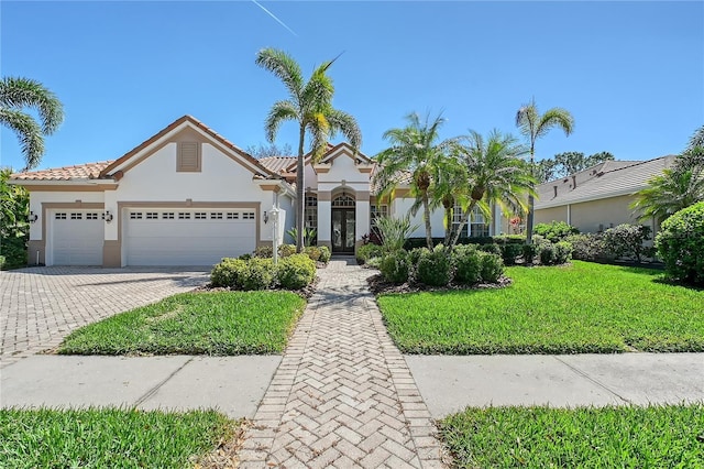 mediterranean / spanish home with a front yard, stucco siding, french doors, a garage, and decorative driveway