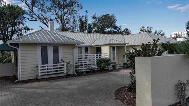 single story home with metal roof, french doors, a standing seam roof, and fence