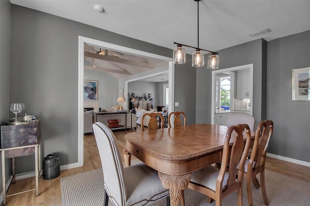 dining area with baseboards, visible vents, beam ceiling, and light wood-style floors