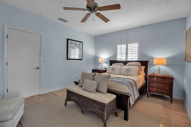 bedroom with baseboards, ceiling fan, visible vents, and light wood-style floors