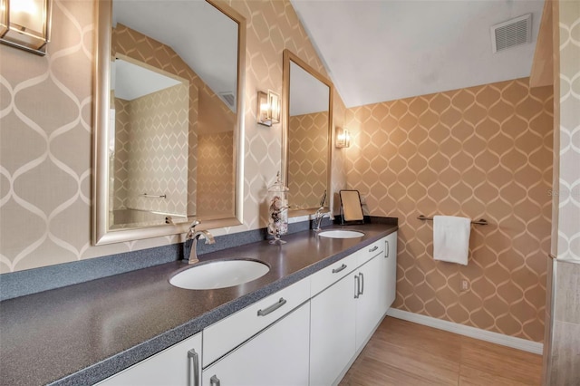 bathroom with double vanity, a sink, visible vents, and baseboards