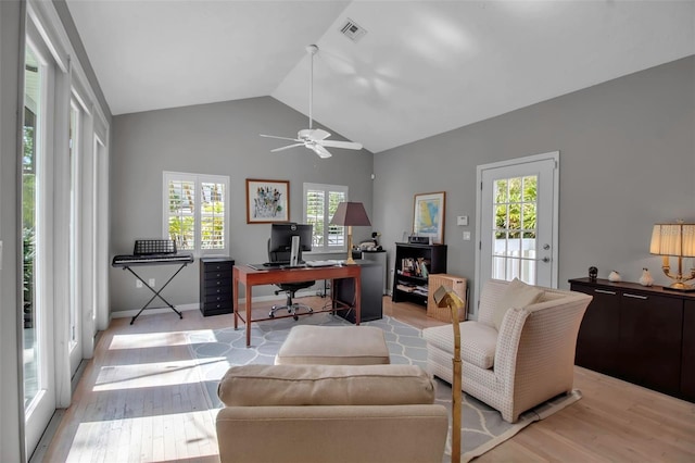 office featuring lofted ceiling, light wood-style floors, visible vents, and a ceiling fan