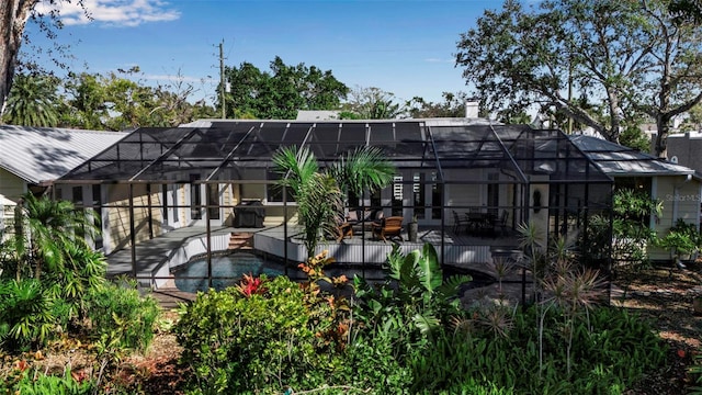 back of house featuring a deck, a lanai, and a chimney