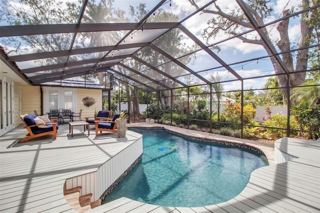 view of swimming pool featuring glass enclosure, outdoor lounge area, french doors, a fenced in pool, and a patio area