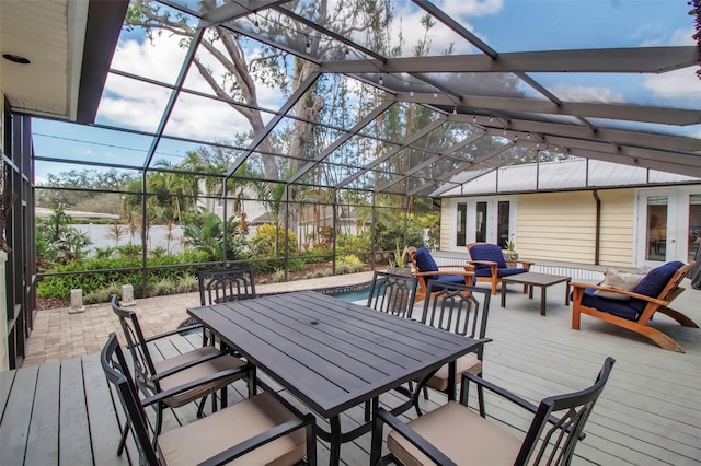 wooden deck featuring a lanai, a water view, a patio area, and a pool