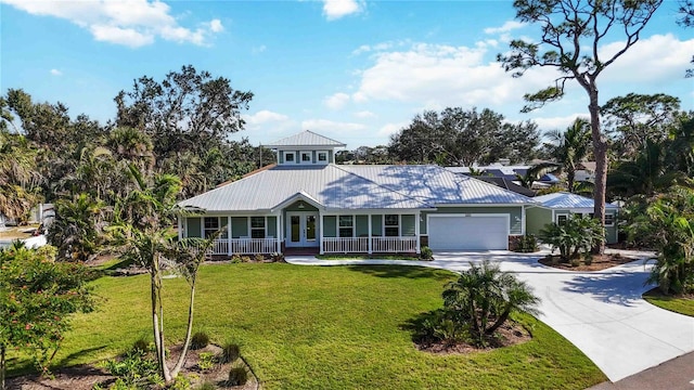 view of front facade with metal roof, an attached garage, covered porch, driveway, and a front lawn