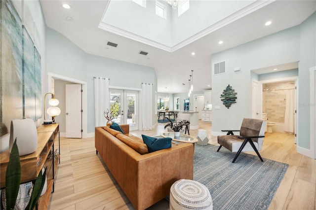 living room with light wood-style floors, french doors, visible vents, and a high ceiling