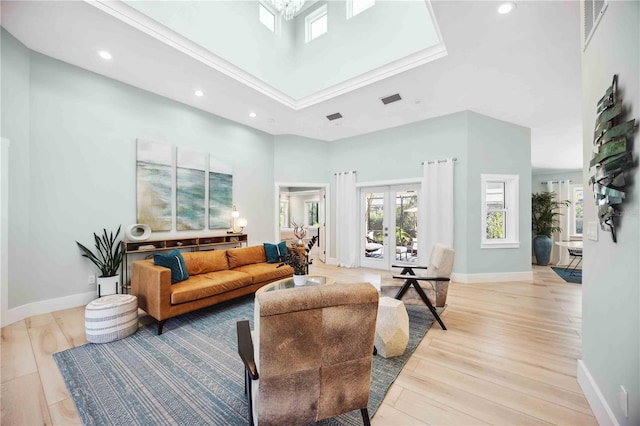 living area featuring a towering ceiling, light wood-style floors, visible vents, and french doors