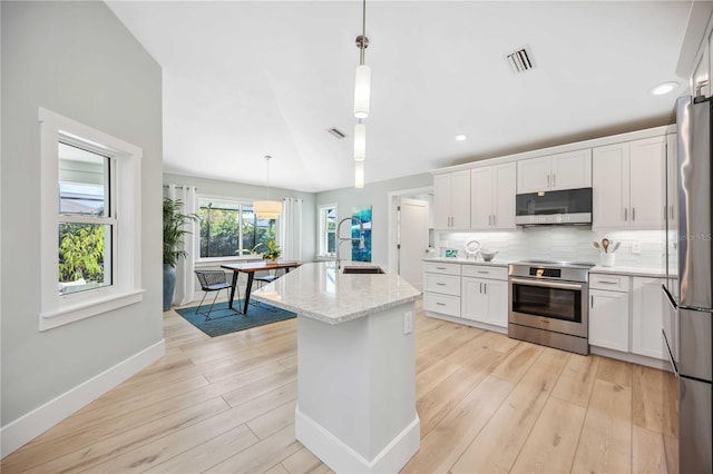 kitchen featuring appliances with stainless steel finishes, a sink, white cabinetry, and decorative light fixtures