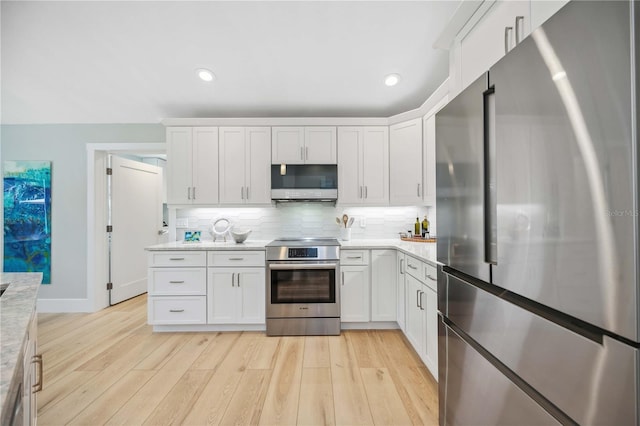 kitchen with recessed lighting, light wood-style floors, white cabinets, appliances with stainless steel finishes, and decorative backsplash