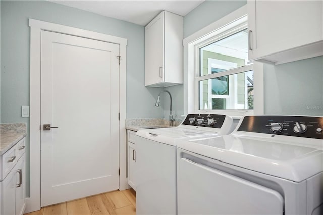 laundry room with washing machine and dryer, cabinet space, a sink, and light wood finished floors