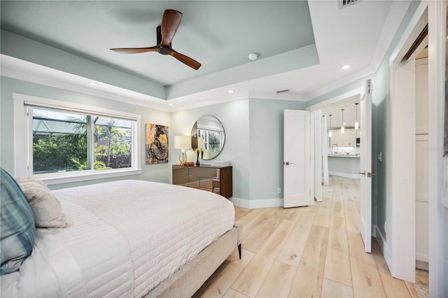 bedroom with recessed lighting, light wood-type flooring, a raised ceiling, and baseboards