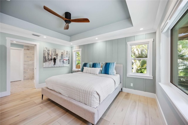 bedroom with light wood-style floors, visible vents, a raised ceiling, and recessed lighting