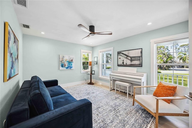 living room featuring a ceiling fan, wood finished floors, visible vents, and baseboards