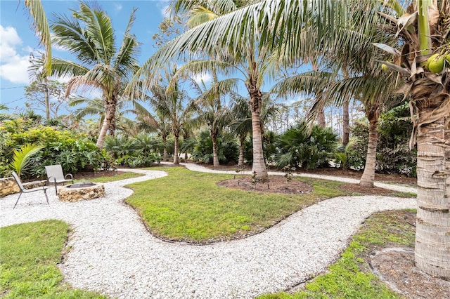 view of property's community with an outdoor fire pit and a lawn